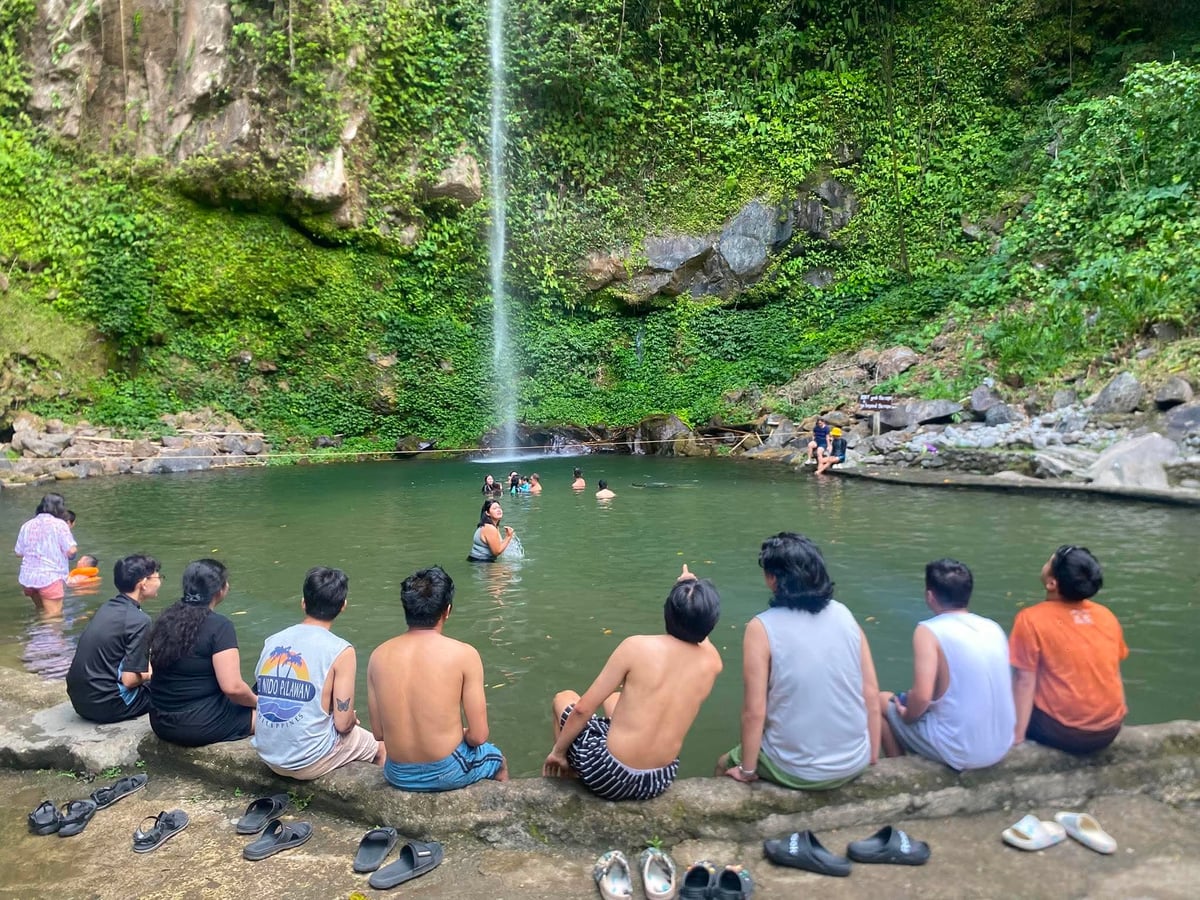 The NorthQA team sitting by a waterfall pool in Camiguin