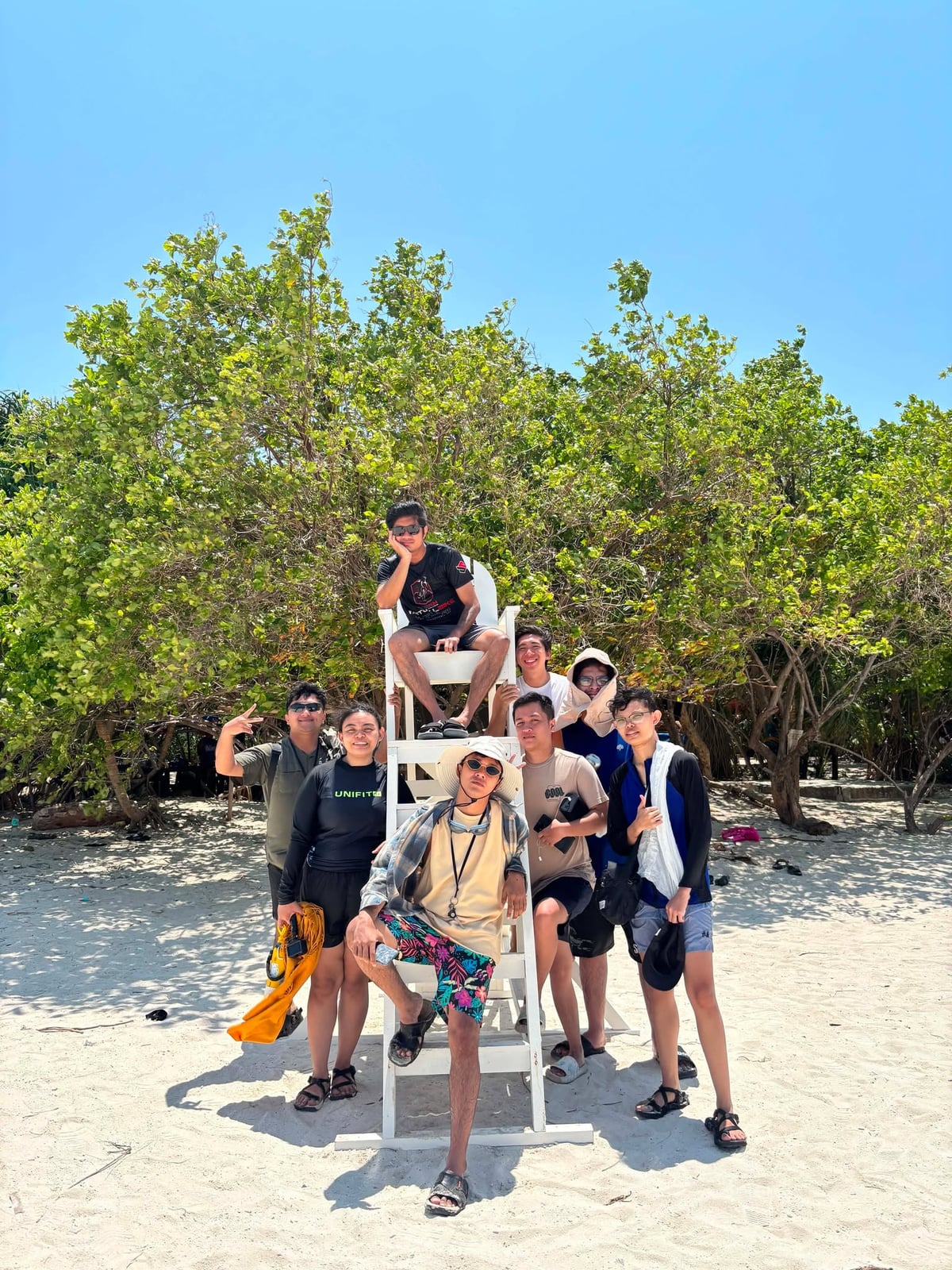 The NorthQA team gathered around a lifeguard tower on the beach